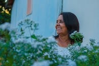 Joyful woman amidst white flowers, enjoying a bright day outdoors.